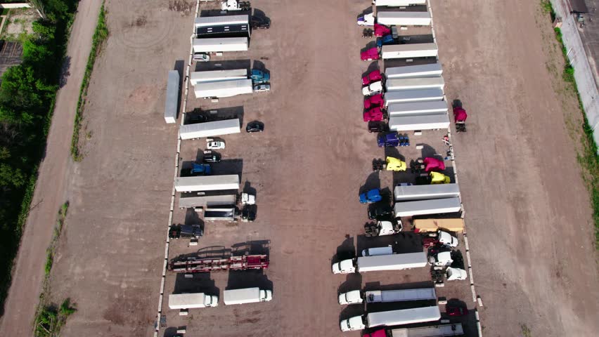 yard parking lot with semi trucks and trailers - reefers, dry van, flatbeds, stingers, bob tails. Truck Driver is backing up. Plainfield Illinois USA