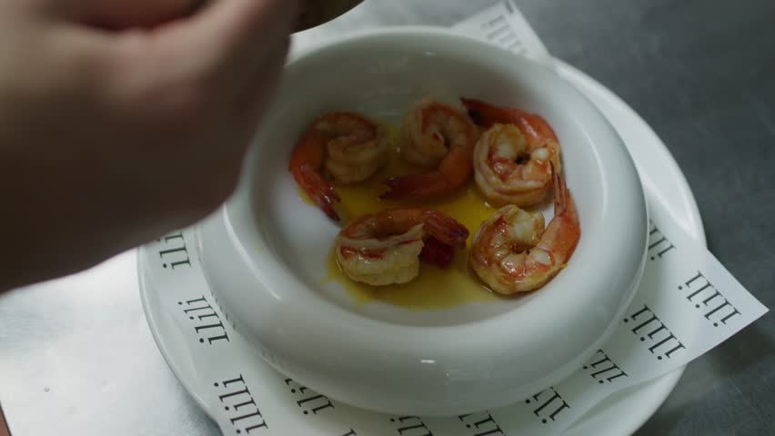 Chef pouring olive oil over Mediterranean fresh seafood shrimp soup, traditional healthy dish