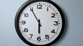 Closeup of White Clock Face on white wall clock, arrows show 6:00 or 00:00