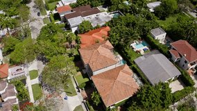 Aerial drone Footage in Miami, Florida, USA, commercial area, luxury houses, buildings and mansions, abundant tropical vegetation around, blue sky and Ocean.