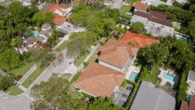 Aerial drone Footage in Miami, Florida, USA, commercial area, luxury houses, buildings and mansions, abundant tropical vegetation around, blue sky and Ocean.