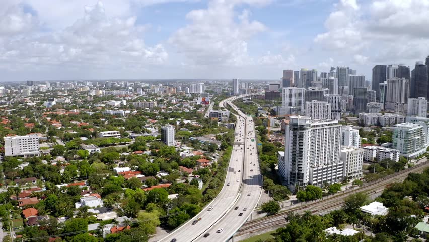 Aerial drone Footage in Miami, Florida, USA, commercial area, luxury houses, buildings and mansions, abundant tropical vegetation around, blue sky and Ocean.