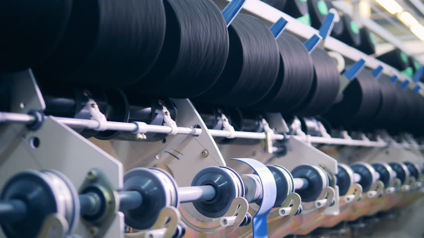 Factory mechanism is rewinding reels with threads. textile production, textile industry, textile manufacture, textile manufacturing