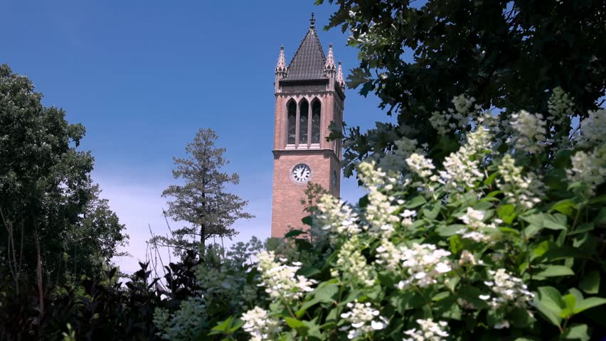 Iowa State University Campanile in Ames, Iowa with view through trees and flowers stable video.