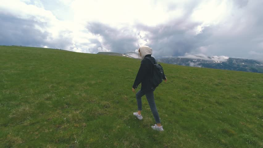 A beautiful Ukrainian young woman traveler walks along the most beautiful high mountain road in Romania Transalpina highway at day. Transalpina, Carpathian mountains in Romania