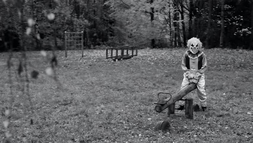 Halloween clown.black and white video. scary clown swings on a wooden swing at the playground in the park. High quality 4k footage Royalty-Free Stock Footage #1106723897