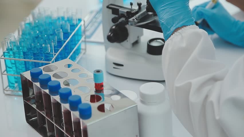 Health care researchers working in life science laboratory. Young female research scientist and senior male supervisor preparing and analyzing microscope slides in research lab. Royalty-Free Stock Footage #1106729353