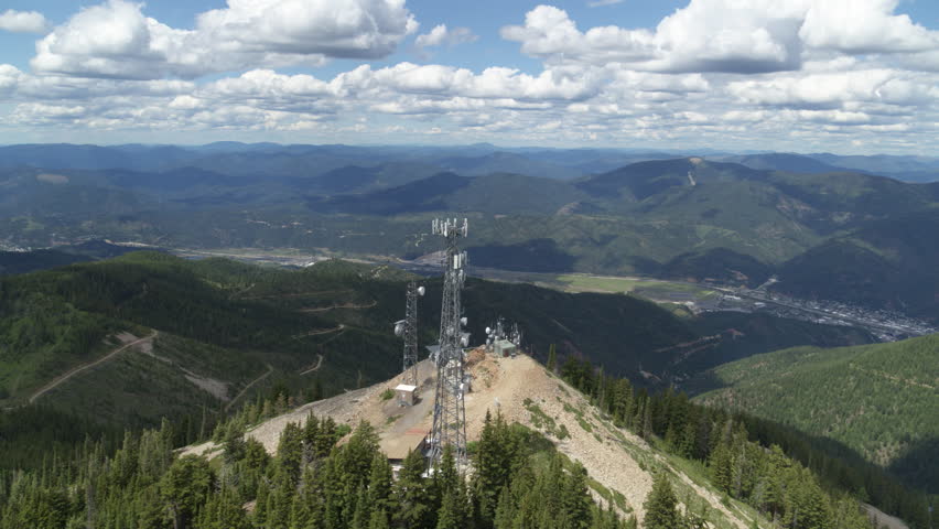 Aerial around cell tower in Kellogg Idaho on peak of mountain in summer