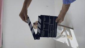 Young woman actress sitting in armchair. Using movie clapperboard audition in white studio. Vertical 4k footage. 