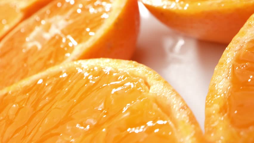 Macro video, a group of oranges slices is captured in exquisite detail. With a probe lens, each vibrant half reveals intricate patterns, textures, and juicy segments. Fruit concept. Orange background
