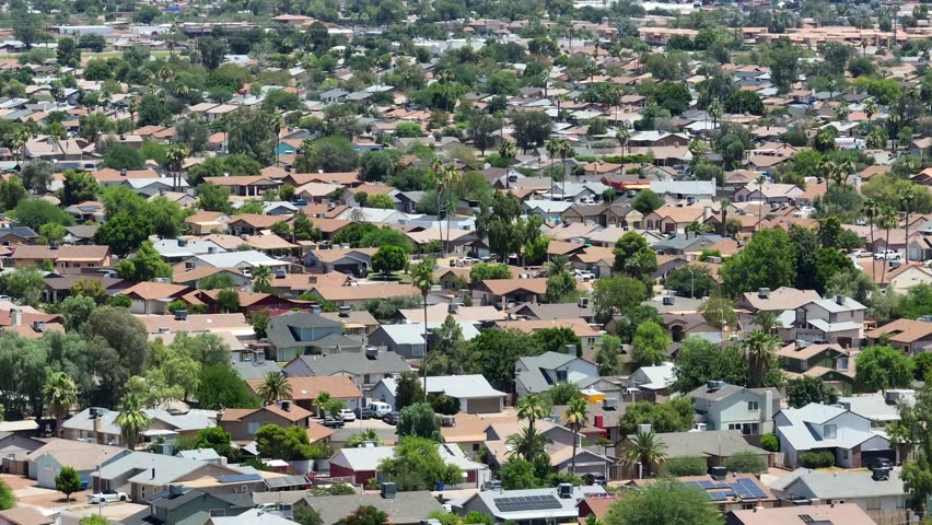 Sprawling neighborhoods in suburb of large American city. Aerial tilt up reveal of urban skyline. Houses and homes in southwest USA housing developments.