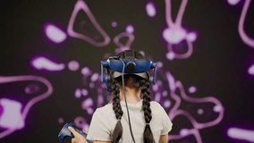 The cute little girl wearing VR headset in virtual reality. The child in modern virtual reality paint and fly. Blur background. Concept paint, fly in VR headset, children leisure in virtual reality