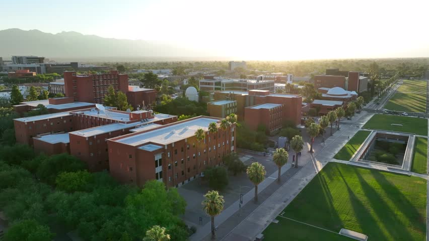Cinematic aerial establishing shot of academic buildings on college campus of University of Arizona. Beautiful sunrise over Tucson, Arizona school landscape.