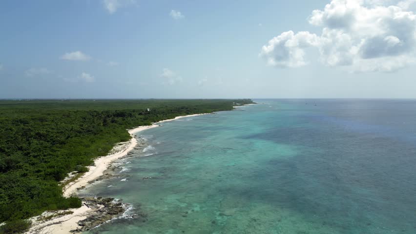 Drone footage rolling left over a turquoise ocean and coral reef in the Caribbean (Cayman Islands) with native forest stretching along the beach into the horizon as clouds cast shadows over the water. Royalty-Free Stock Footage #1106755359