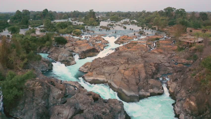 Slow travelling of Li Phi Somphamit Waterfalls at sunset. Drone aerial view with camera panning down. Tourist travel destination of the 4000 islands in Mekong, Laos. Royalty-Free Stock Footage #1106759167