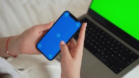 Close up teenage hands using smartphone green blue screen Chroma Key. Child girl scrolling over laptop app background Online entertainment education, online shopping, gaming, Mobile app, Using