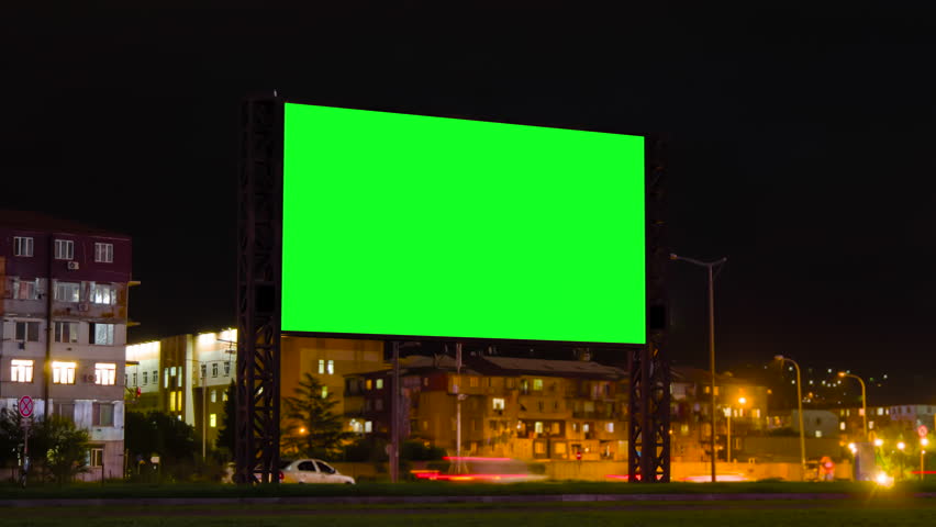 Timelapse: blank green billboard, large display, fast moving car traffic and light trails in evening time with warm night lighting. Green screen, time lapse, mock up and copy space concept Royalty-Free Stock Footage #1106761449