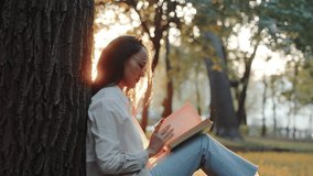 Beautiful asian young woman in glasses sitting under tree and reading a book at sunset. Lady with book resting relaxing in the city park. Enjoying vacation - Powered by Shutterstock - Get 15% off with code: PIKWIZARD15