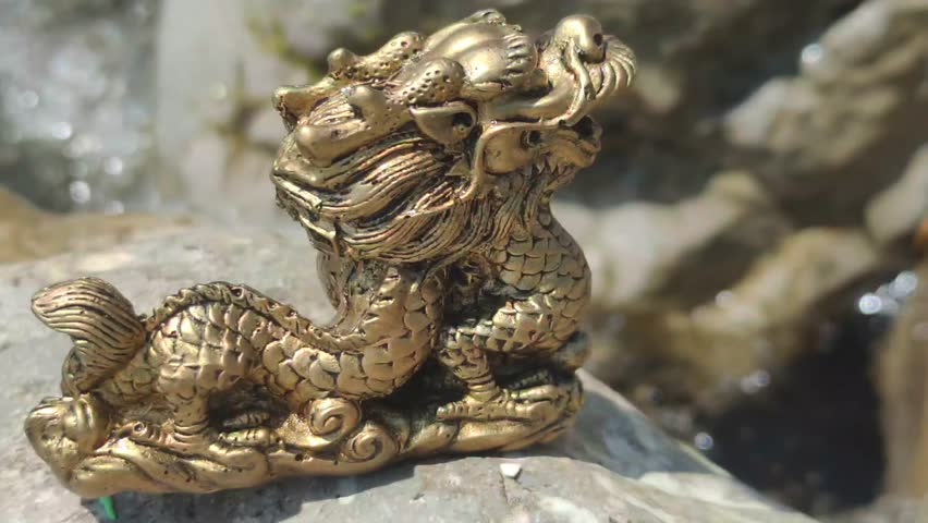 Figurine of a Chinese golden dragon on the seashore in summer.