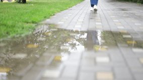 The legs of a young white woman jump over a puddle. She happily enjoys solitude and peace. Walking in the rain in white sneakers. Spring - Powered by Shutterstock - Get 15% off with code: PIKWIZARD15