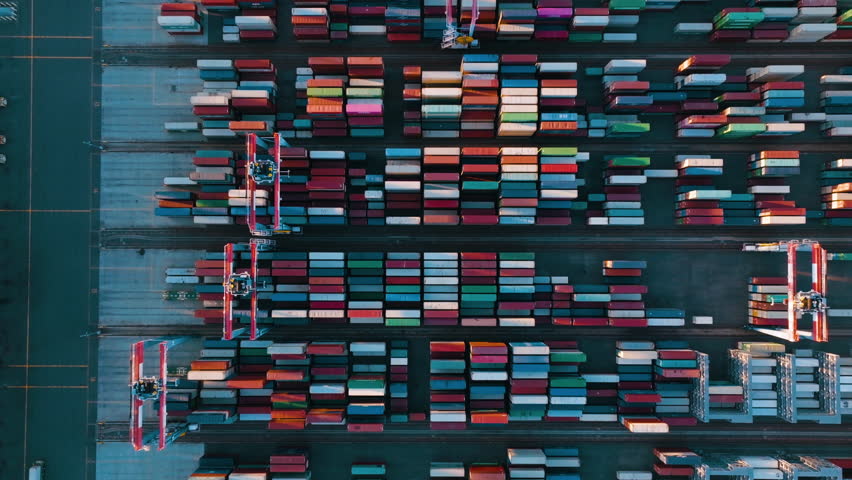 Drone view of shipping containers in a busy port. Logistics, transportation and shipment shot from above. 
Many containers moored in port. Aerial vertical, vertical video background.
