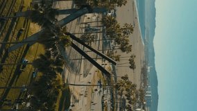 Venice Beach Drone in Los Angeles, CA with beautiful sunshine during summer on the Beachfront Skatepark Skaters Park. Aerial vertical, vertical video background.