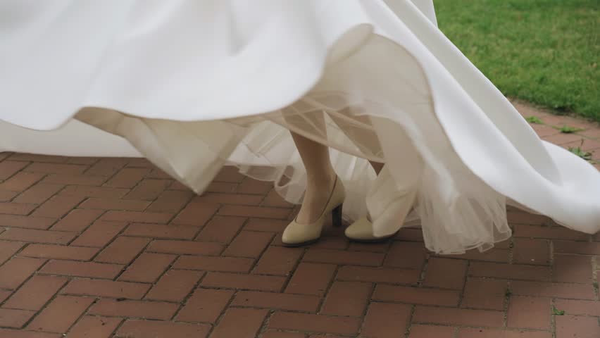 A girl in a white dress is spinning around herself. The hem of the dress moves beautifully in slow motion