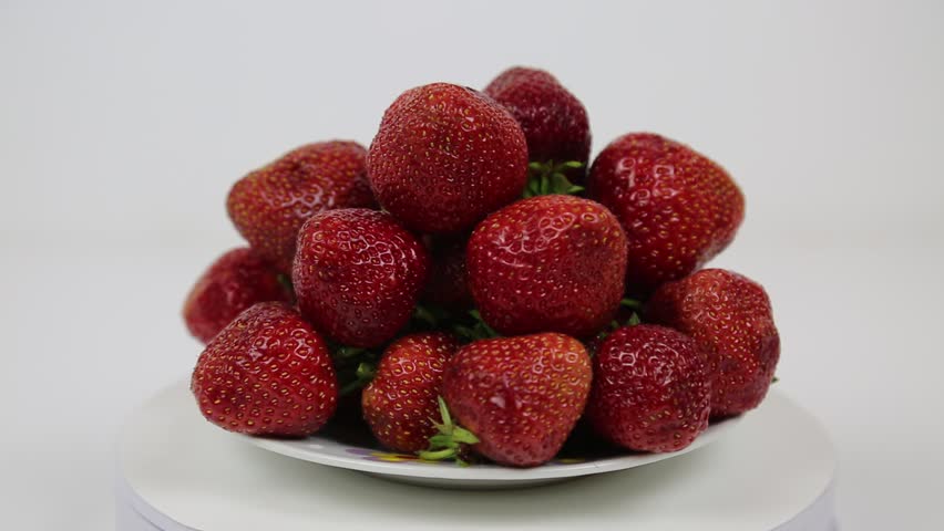 Strawberries of bright red color in a pile on a plate rotate on a white background. Raw organic fruits. Useful products. | Shutterstock HD Video #1106775541