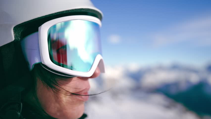 Close-up portrait of woman snowboarder skyer in ski helmet and glasses in mountains, side view. Girl wearing in ski clothes in winter resort. Enjoy healthy sport active rest, snowboarding lifestyle. Royalty-Free Stock Footage #1106777115