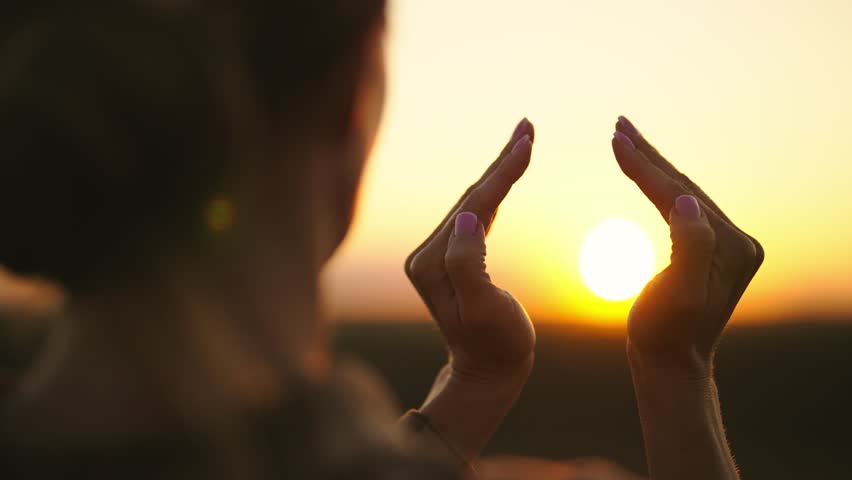 Woman folding hands around sun at sunset in romb shape, symbol of peace and meditation, rear view. Relax, healthy lifestyle, balance, harmony concept. Female in unity with nature, enjoying evening. Royalty-Free Stock Footage #1106777161
