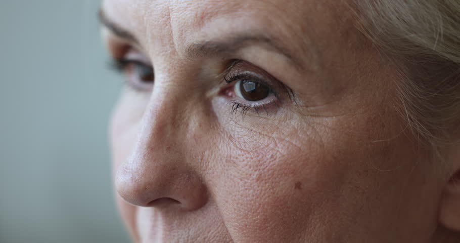 Upper face close up shot of sad elderly mature lady with tired brown eyes, black mascara looking away. Senior model woman with makeup, dry facial skin with wrinkles. Cropped shot Royalty-Free Stock Footage #1106786909