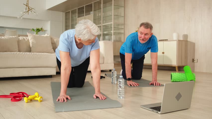 Fitness workout training. Senior adult mature healthy fit couple doing sports exercise on yoga mat on floor at home. Mid age old husband wife have training workout. Health care healthy lifestyle