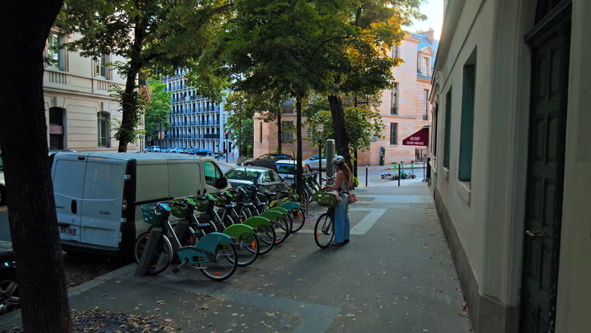 A young woman dropped off the bike at the bike station. A young tourist taking off the helmet after a bike ride.