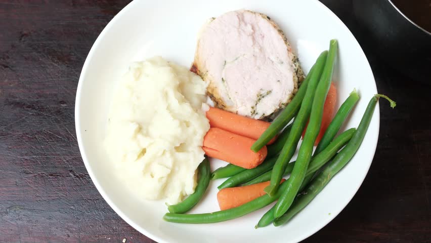 Adding gravy to traditional turkey dinner. Top view