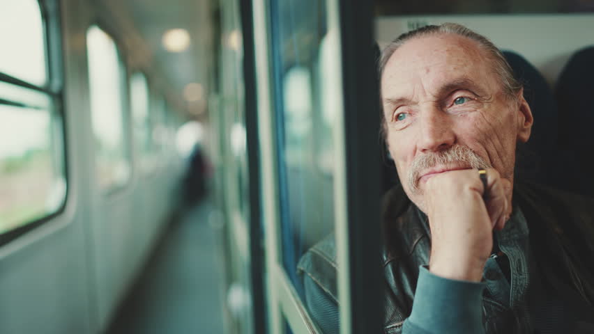 Closeup portrait of elderly man looking out of coupe window while traveling in train