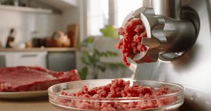 Electric meat grinder mince beef and pork meat in kitchen in daylight. Soft blurred background. Slow Static shoot. Advertising. Meat grinder with freshly ground meat. Concept healthy nutrition routine