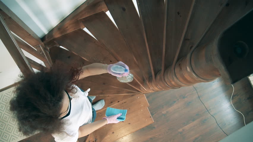 Young woman wipes stairs with sanitizer during quarantine.