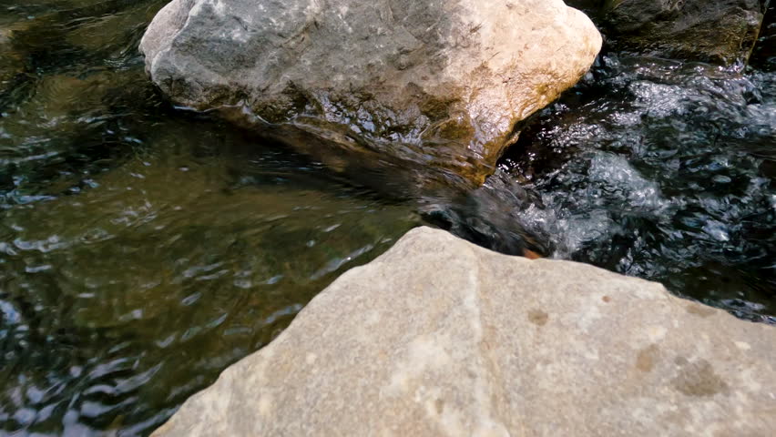 Closeup views of a flowing river. The water sprays and splashes over the large rocks in the river. Located within Shawnee National Forest in Southern Illinois, USA.