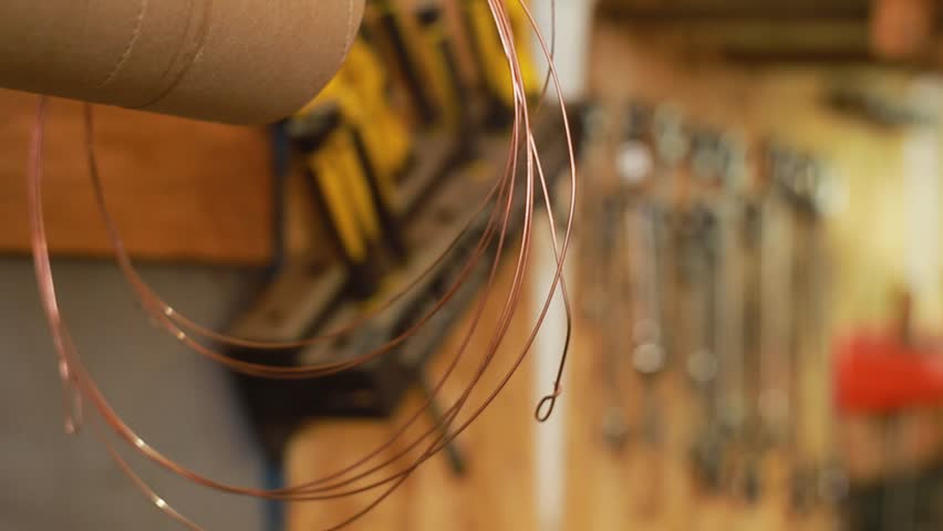 Copper metal wire, a set of bits and screwdrivers, wrenches, hexagons and other tools hang on a wooden wall in a repair shop. Move focus from foreground to background Royalty-Free Stock Footage #1106814385
