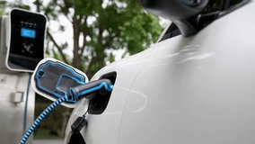 Electric car recharging battery by futuristic smart EV charger from eco clean energy charging station in natural green car park. Futuristic eco-friendly electric car using alternative energy. Peruse - Powered by Shutterstock - Get 15% off with code: PIKWIZARD15