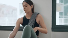 Video of sporty young woman drinking protein shake after gym exercicis sitting on the floor at home