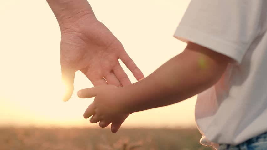 Dad holds out his hand to his son in park at sunset. Happy family, child takes his fathers hand in sun, closeup. Family trust concept. Slowmotion. Father walks with boy in nature, weekend. parent, kid
