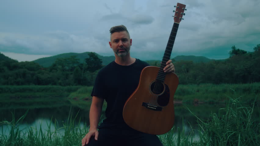 portrait of guitarist oudoors in the countryside 
