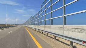 Protective screens along the freeway. Video shooting in motion, the effect of speed, the car is driving on the highway near the fence. Dust, wind, road noise insulation. fence from the side of the