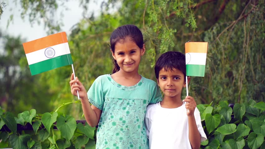 Indian students or children holding or waving Tricolour with greenery in the background, celebrating Independence or Republic day