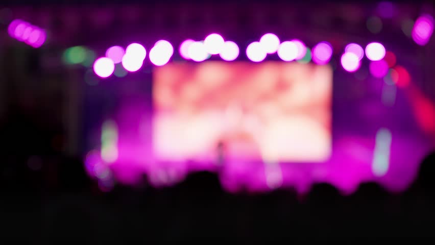 Happy people watching amazing musical concert. Bright colorful stage lighting. Selective focus, blurred. Nightlife and entertainment concept. People with raised arms on music event with lights Royalty-Free Stock Footage #1106826867