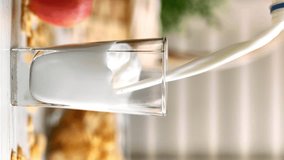 VERTICAL VIDEO POV pouring milk from bottle to glass fresh organic beverage calcium nutritious slow motion. Healthy dairy product nourishment adding stream for breakfast with corn flakes and apple - Powered by Shutterstock - Get 15% off with code: PIKWIZARD15