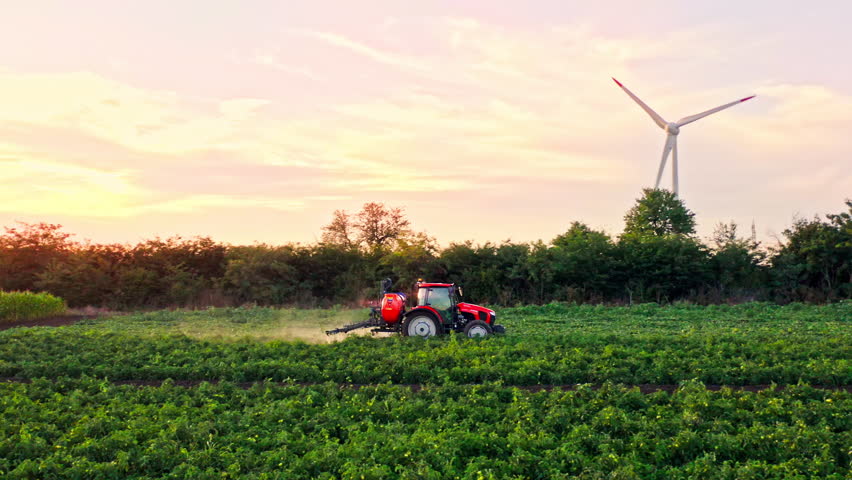 Zoom out span from drone of crop sprayer traktor spraying pesticide or herbicides field. Wind turbines on background. Modern agriculture. Leasing of tractors and agricultural machinery Royalty-Free Stock Footage #1106832793