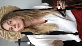 a beautiful girl in front of the mirror sprays perfume, steps back and waves her hand at the camera. a woman in a straw hat, sunglasses and a brown handbag is posing. vertical video - Powered by Shutterstock - Get 15% off with code: PIKWIZARD15