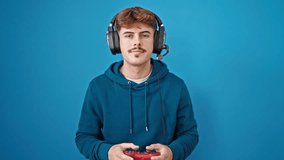 Young hispanic man playing video game celebrating over isolated blue background